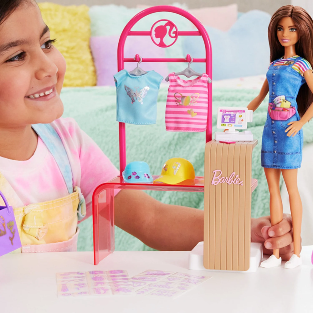 Barbie Make & Sell Boutique Playset with Brunette Doll, Foil Design Tools, Clothes & Accessories. Kids can stitch their way into the fashion world with the Barbie Make & Sell Boutique playset! HKT78 thumbnail